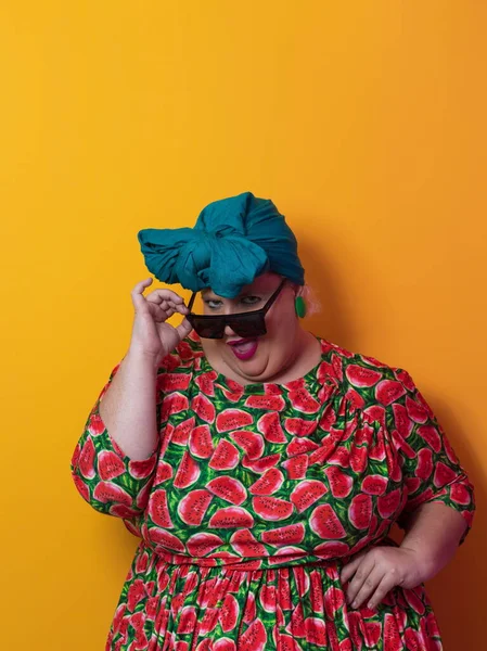 Funny plus size sexy model woman with trendy sunglasses, fashionable overweight blonde in colorful dress posing at the yellow background in studio. — ストック写真