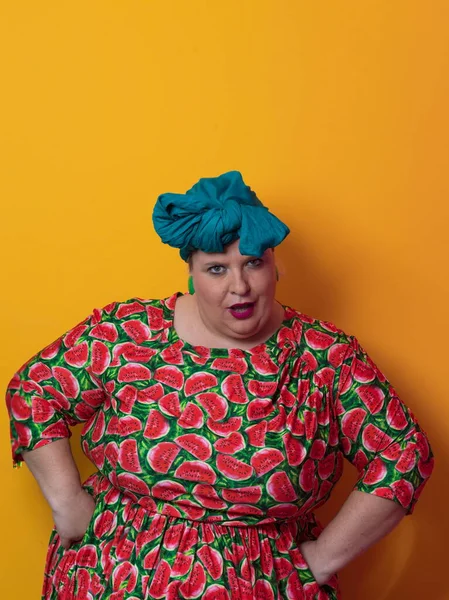 Funny plus size sexy model woman with trendy makeup, fashionable overweight blonde in colorful dress posing at the yellow background in studio. — ストック写真