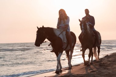 Aile kumlu bir sahilde birlikte ata binerken çocuklarıyla vakit geçirir. Seçici odak 