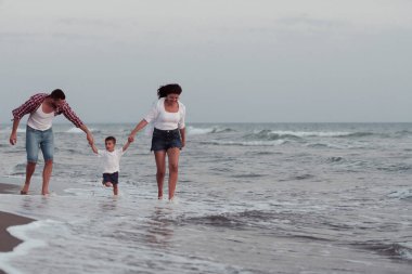 Aile, oğluyla kumsalda yürürken tatilin tadını çıkarıyor. Seçici odak 