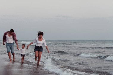 Aile, oğluyla kumsalda yürürken tatilin tadını çıkarıyor. Seçici odak 