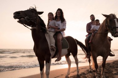 Aile kumlu bir sahilde birlikte ata binerken çocuklarıyla vakit geçirir. Seçici odak 