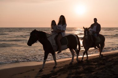 Aile kumlu bir sahilde birlikte ata binerken çocuklarıyla vakit geçirir. Seçici odak 