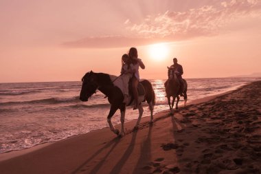 Aile kumlu bir sahilde birlikte ata binerken çocuklarıyla vakit geçirir. Seçici odak 