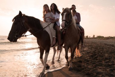 Aile kumlu bir sahilde birlikte ata binerken çocuklarıyla vakit geçirir. Seçici odak 