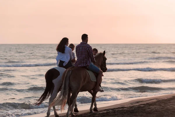 A família passa tempo com seus filhos enquanto montam cavalos juntos em uma praia de areia. Foco seletivo — Fotografia de Stock