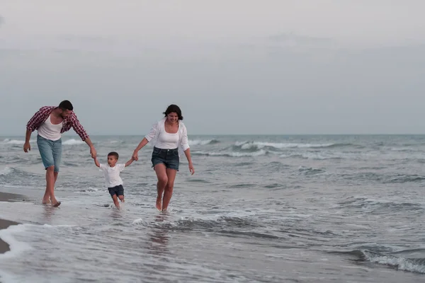 The family enjoys their vacation as they walk the sandy beach with their son. Selective focus — Stok fotoğraf