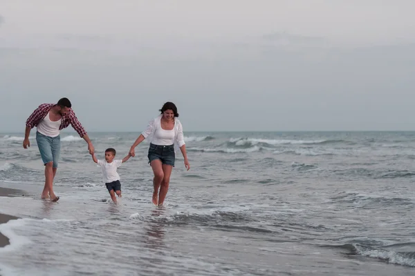 The family enjoys their vacation as they walk the sandy beach with their son. Selective focus — 图库照片