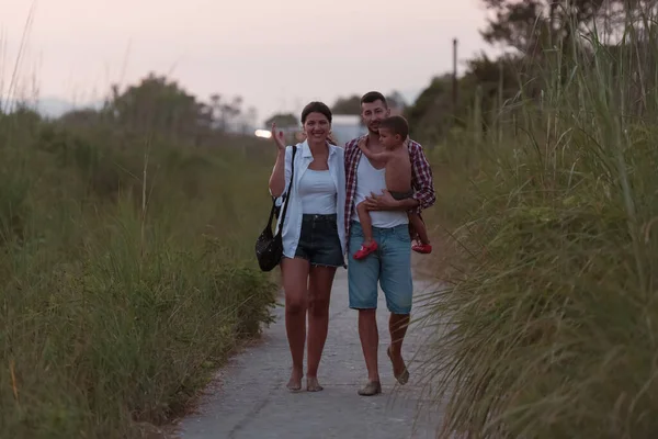 The family walks an idyllic path surrounded by tall grass. Selective focus — Stockfoto