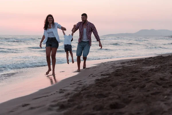 Сім'я насолоджується відпусткою, коли вони гуляють піщаним пляжем зі своїм сином. Вибірковий фокус — стокове фото