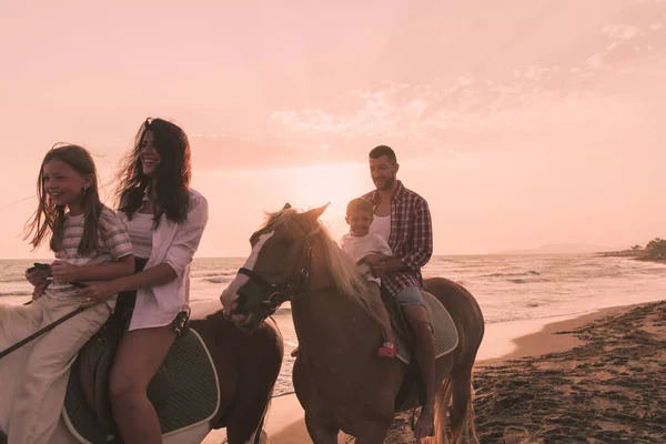 A família passa tempo com seus filhos enquanto montam cavalos juntos em uma praia de areia. Foco seletivo — Fotografia de Stock