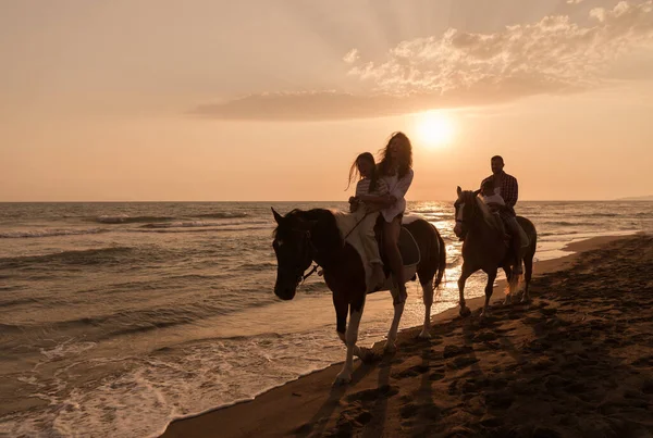 La familia pasa tiempo con sus hijos mientras cabalgan juntos en una playa de arena. Enfoque selectivo — Foto de Stock