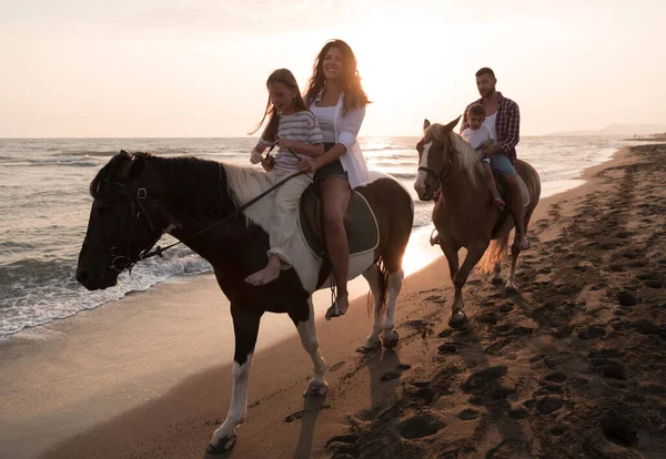 Die Familie verbringt Zeit mit ihren Kindern, während sie gemeinsam auf Pferden am Sandstrand reiten. Selektiver Fokus — Stockfoto