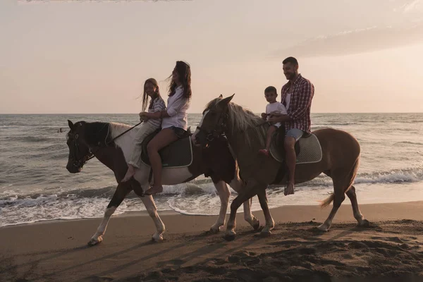 La familia pasa tiempo con sus hijos mientras cabalgan juntos en una playa de arena. Enfoque selectivo — Foto de Stock