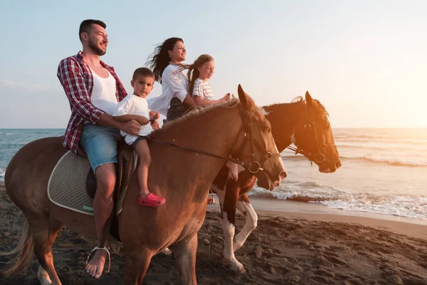 La famiglia trascorre del tempo con i propri figli a cavallo su una spiaggia sabbiosa. Focus selettivo — Foto Stock
