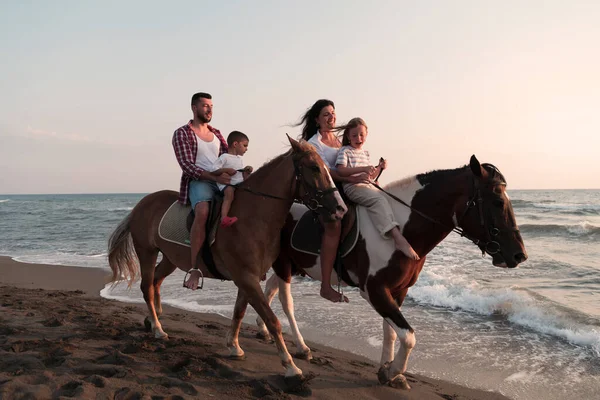 The family spends time with their children while riding horses together on a sandy beach. Selective focus — Φωτογραφία Αρχείου