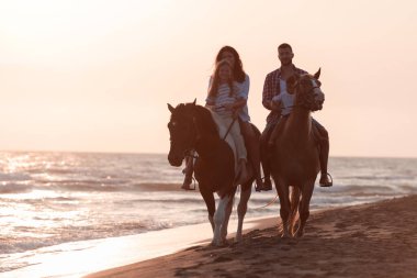 Aile kumlu bir sahilde birlikte ata binerken çocuklarıyla vakit geçirir. Seçici odak 