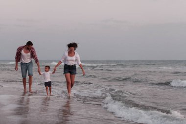 Aile, oğluyla kumsalda yürürken tatilin tadını çıkarıyor. Seçici odak 