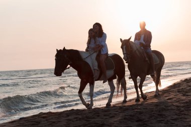 Aile kumlu bir sahilde birlikte ata binerken çocuklarıyla vakit geçirir. Seçici odak 