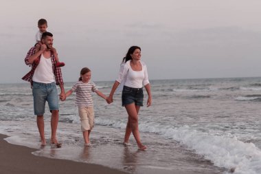 Aile toplantıları ve gün batımında sahilde sosyalleşme. Aile kumlu sahil boyunca yürür. Seçici odak 