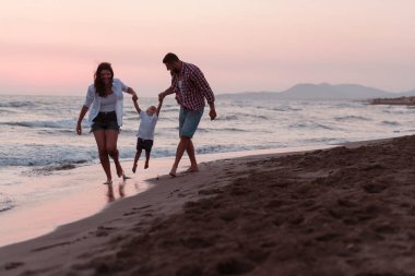 Aile, oğluyla kumsalda yürürken tatilin tadını çıkarıyor. Seçici odak 