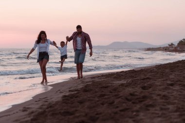 Aile, oğluyla kumsalda yürürken tatilin tadını çıkarıyor. Seçici odak 
