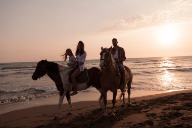 Aile kumlu bir sahilde birlikte ata binerken çocuklarıyla vakit geçirir. Seçici odak 
