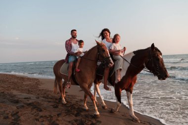 Aile kumlu bir sahilde birlikte ata binerken çocuklarıyla vakit geçirir. Seçici odak 