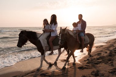 Aile kumlu bir sahilde birlikte ata binerken çocuklarıyla vakit geçirir. Seçici odak 