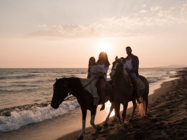 Aile kumlu bir sahilde birlikte ata binerken çocuklarıyla vakit geçirir. Seçici odak 