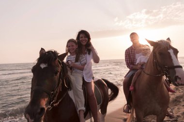 Aile kumlu bir sahilde birlikte ata binerken çocuklarıyla vakit geçirir. Seçici odak 