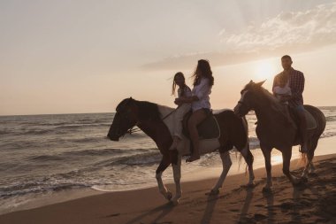 Aile kumlu bir sahilde birlikte ata binerken çocuklarıyla vakit geçirir. Seçici odak 