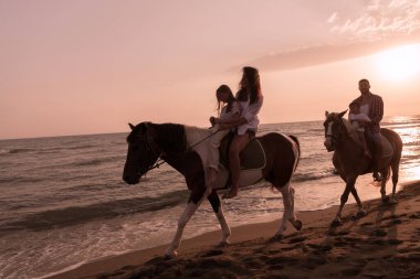 Aile kumlu bir sahilde birlikte ata binerken çocuklarıyla vakit geçirir. Seçici odak 
