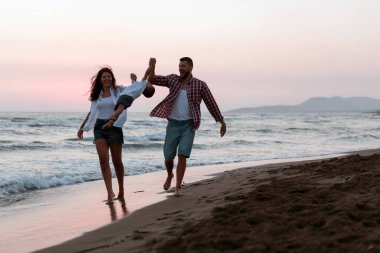 Aile, oğluyla kumsalda yürürken tatilin tadını çıkarıyor. Seçici odak 