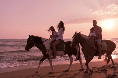 Aile kumlu bir sahilde birlikte ata binerken çocuklarıyla vakit geçirir. Seçici odak 