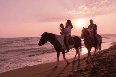 Aile kumlu bir sahilde birlikte ata binerken çocuklarıyla vakit geçirir. Seçici odak 