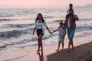 Aile toplantıları ve gün batımında sahilde sosyalleşme. Aile kumlu sahil boyunca yürür. Seçici odak 