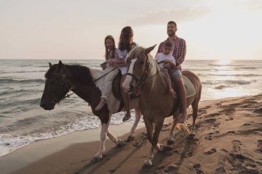 Aile kumlu bir sahilde birlikte ata binerken çocuklarıyla vakit geçirir. Seçici odak 