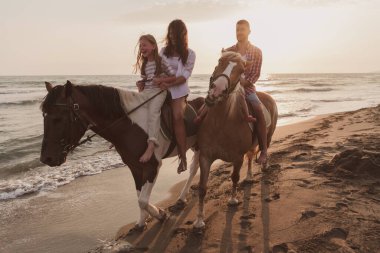 Aile kumlu bir sahilde birlikte ata binerken çocuklarıyla vakit geçirir. Seçici odak 