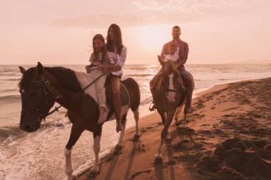 Aile kumlu bir sahilde birlikte ata binerken çocuklarıyla vakit geçirir. Seçici odak 