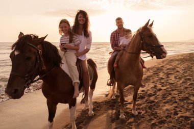 Aile kumlu bir sahilde birlikte ata binerken çocuklarıyla vakit geçirir. Seçici odak 