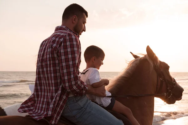 Father and son enjoy riding horses together by the sea. Selective focus — Stock fotografie