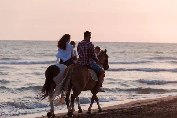 Die Familie verbringt Zeit mit ihren Kindern, während sie gemeinsam auf Pferden am Sandstrand reiten. Selektiver Fokus — Stockfoto