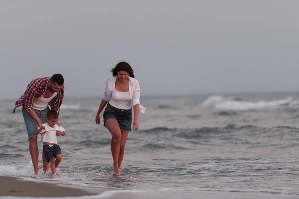 Rodzina cieszy się wakacjami, spacerując po piaszczystej plaży z synem. Skupienie selektywne — Zdjęcie stockowe