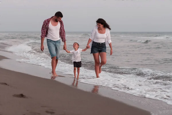 The family enjoys their vacation as they walk the sandy beach with their son. Selective focus — Fotografia de Stock