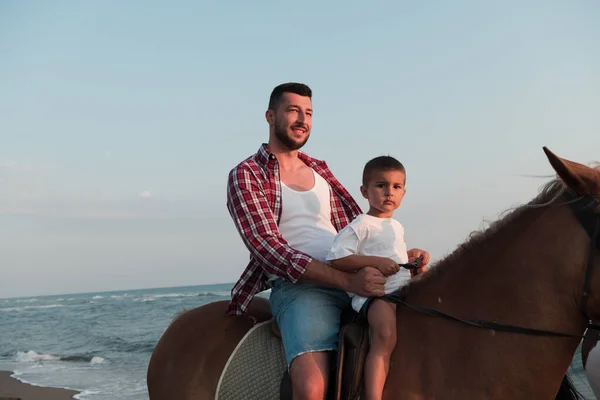 Father and son enjoy riding horses together by the sea. Selective focus — 图库照片