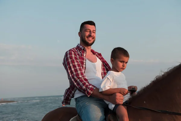 Father and son enjoy riding horses together by the sea. Selective focus — Photo