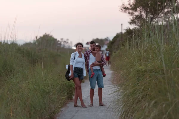 The family walks an idyllic path surrounded by tall grass. Selective focus — 스톡 사진