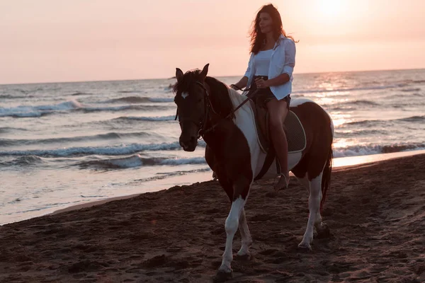 여름 옷을 입은 여자들은 해질 녘에 아름다운 모래사장에서 말을 타는 것을 즐긴다. 선택적 초점 — 스톡 사진