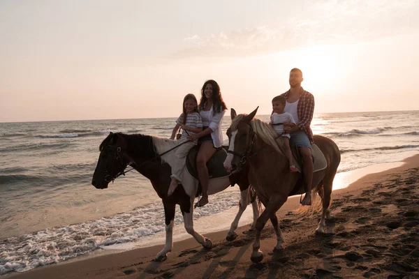 Die Familie verbringt Zeit mit ihren Kindern, während sie gemeinsam auf Pferden am Sandstrand reiten. Selektiver Fokus — Stockfoto